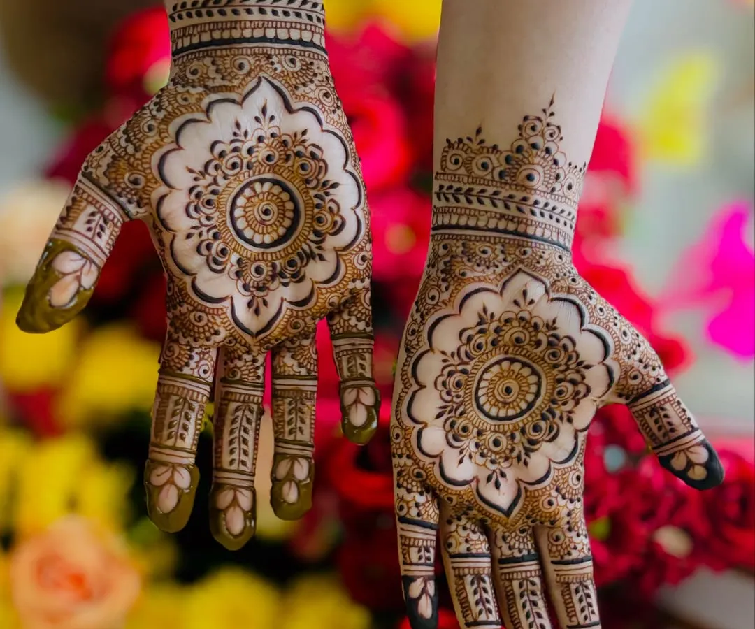 This intricate mandala design is a popular choice for bridesmaids and close family. The bold central flower is complemented by detailed work on the fingers and a delicate wristband, creating a balanced and beautiful look.