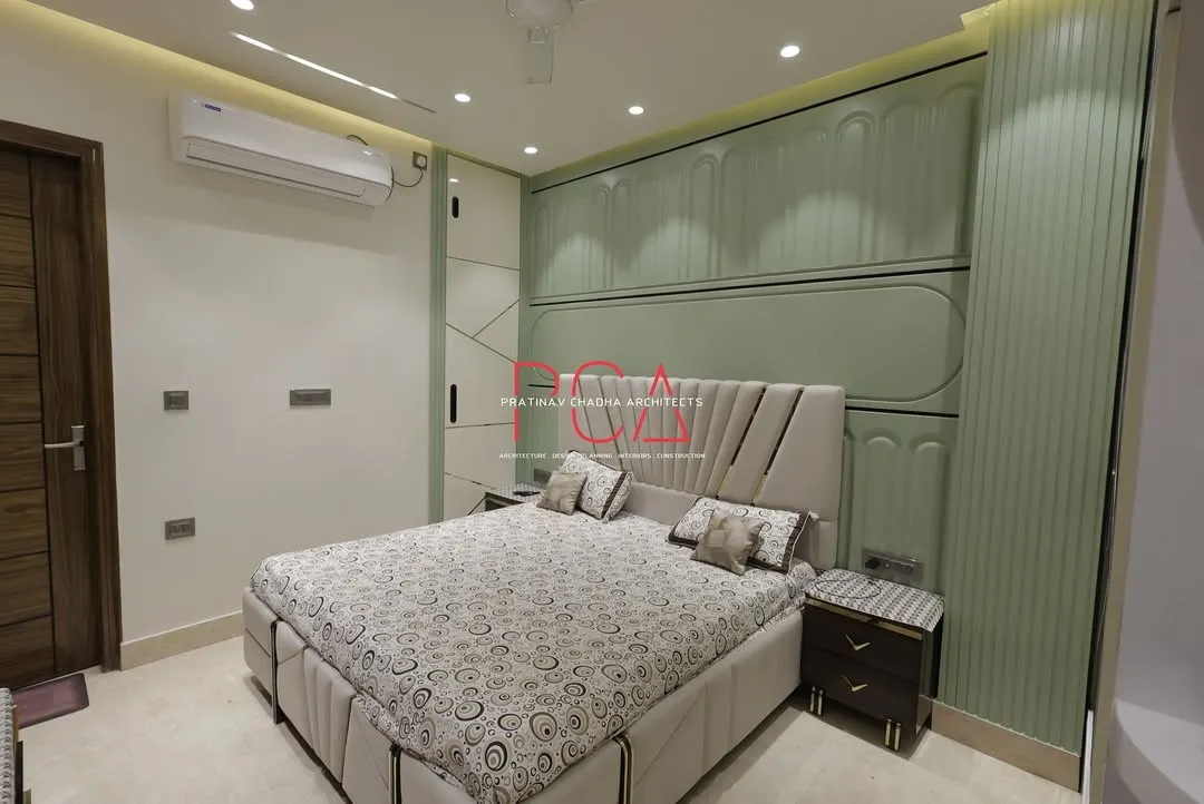 A view of the master bedroom in The Cursive Abode project, showcasing a bespoke design with intricate wall paneling and integrated lighting. The pastel green tones and fluted details create a serene yet sophisticated atmosphere, reflecting my ability to craft personalized and opulent living spaces.