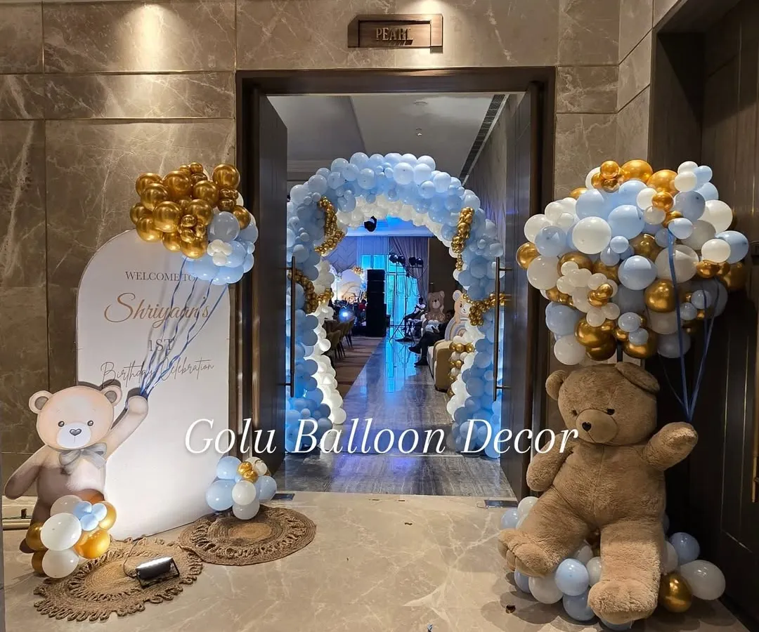 A classic teddy bear theme is always a favorite. Here, I created an inviting entrance for a first birthday with a full balloon arch in pastel blue, white, and gold, flanked by life-sized teddy bears to welcome your guests.