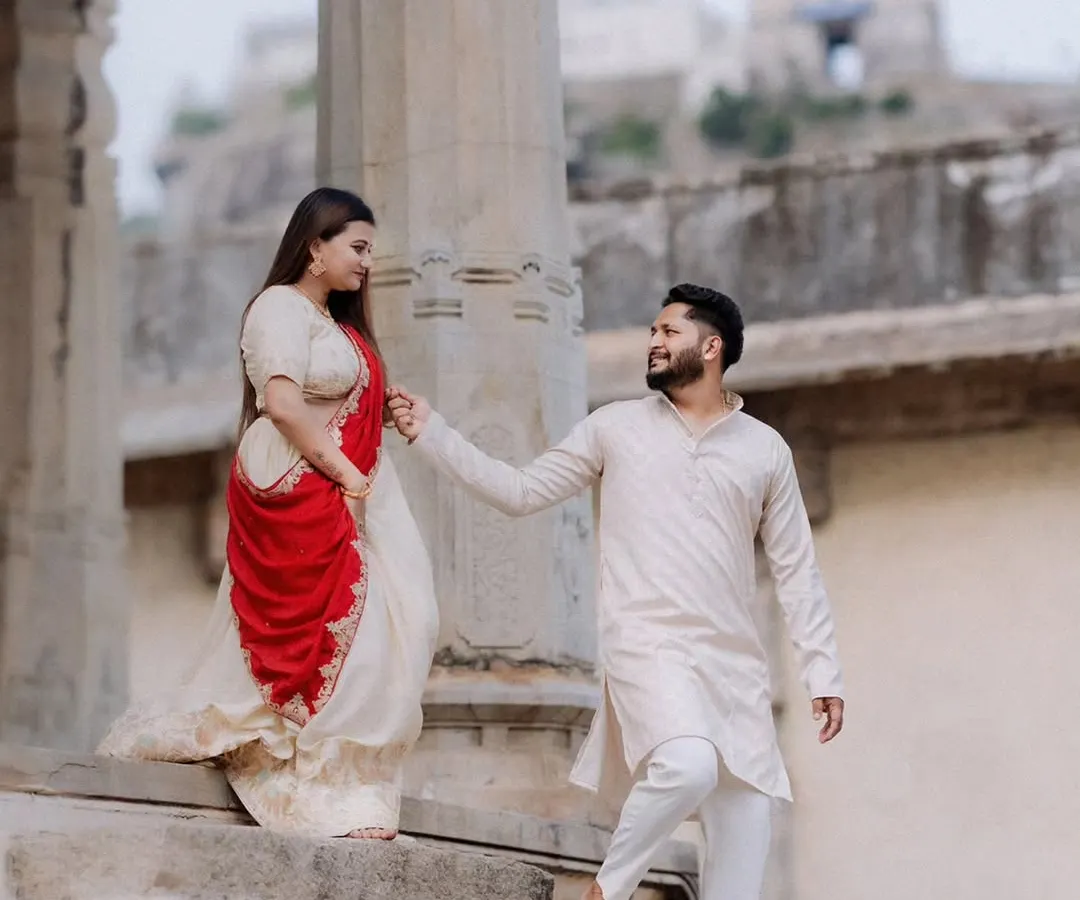 Against the grand, carved stone pillars of a Melukote temple, a couple dressed in traditional attire shares a quiet look. This image showcases a timeless, heritage-themed pre-wedding portrait.