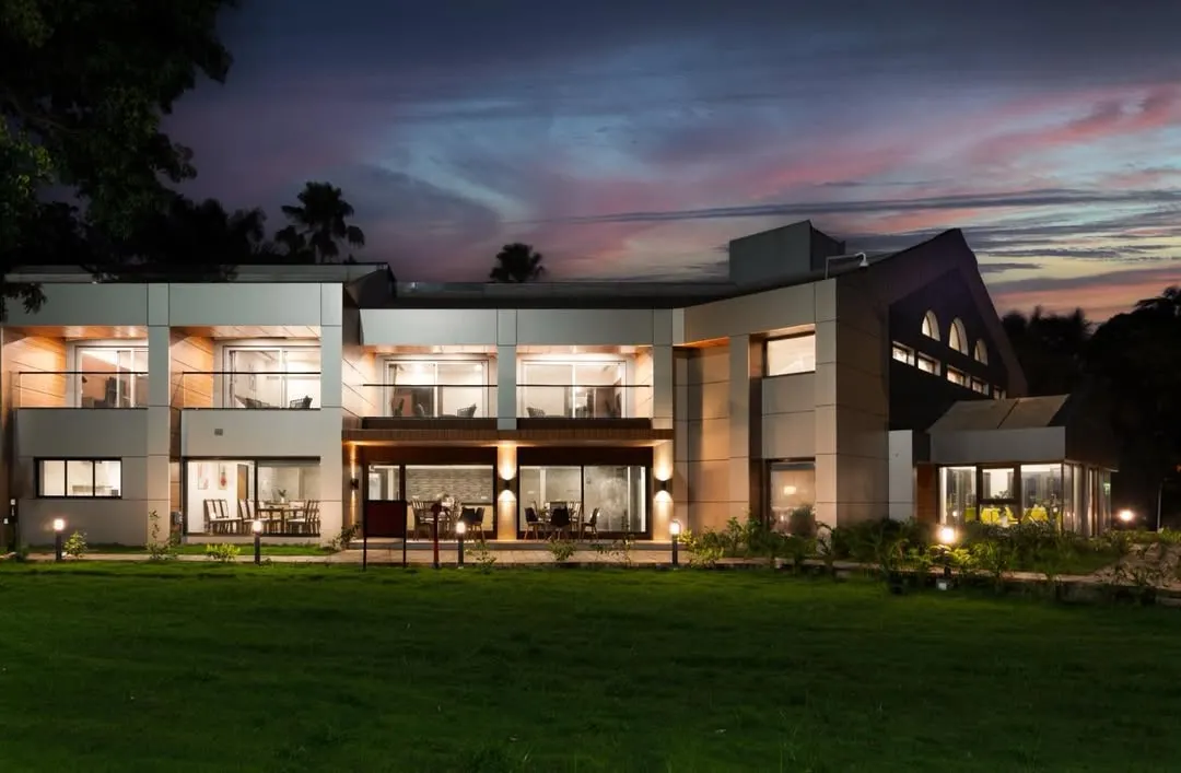 This is the result of our transformation project for the JNPT guesthouse. The architectural design features clean lines, expansive glass, and strategic lighting to create a striking and welcoming presence, especially at twilight.