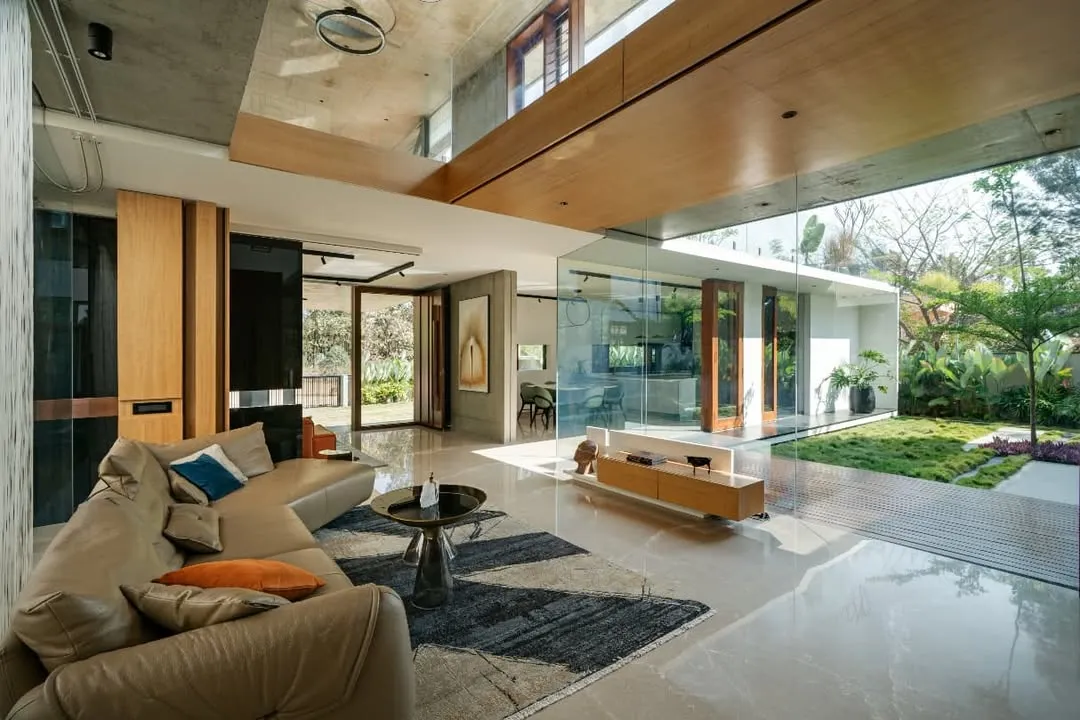 The living space of the Long House dissolves into the central courtyard through expansive glass walls. We designed this to create a seamless flow between the interior and the lush greenery, ensuring the home is filled with natural light and feels like an extension of the garden.