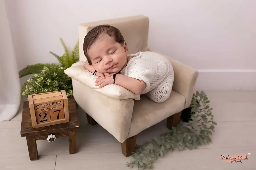 The peaceful, sleepy moments of a newborn are so precious. In my studio, I create a calm and safe space to pose your little one, focusing on capturing their serene innocence and tiny details, like this sweet baby dreaming on a miniature armchair.