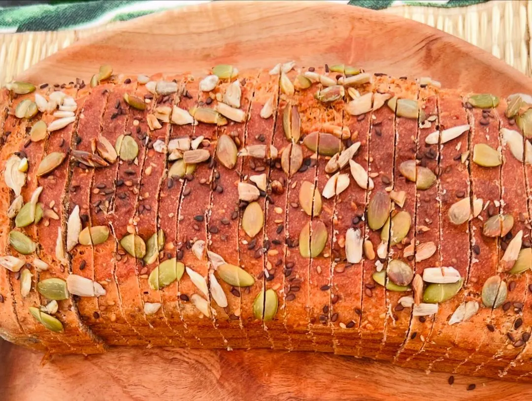 A close look at my signature flourless lentil bread. It's topped with a healthy mix of pumpkin, sunflower, chia, and sesame seeds for extra nutrition and crunch. This is a gluten-free bread you can enjoy without worry.