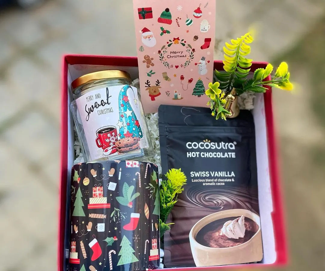 Get cozy for the holidays with our signature Christmas hamper. This set includes a festive mug, a jar of sweet treats, and premium Swiss vanilla hot chocolate mix, all beautifully arranged in a red gift box. It's the perfect warm and thoughtful gift for friends, family, or colleagues.