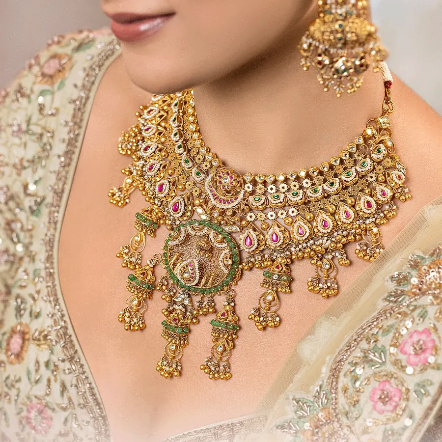 A closer look at the heart of our bridal collection. This exclusive choker, crafted in 22kt gold, showcases a fine Kundan setting, intricate meenakari detailing, and our signature jhumki drops, designed to frame your face with serene radiance.