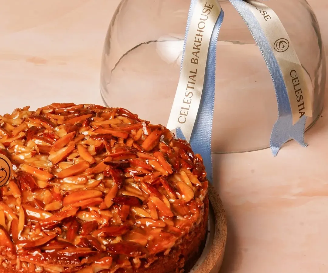 Our Honey Almond Crunch Cake is like a warm hug. It's a buttery soft cake topped with a generous layer of honey-caramelized almonds for the perfect crunch. We present it under this elegant glass cloche, making it a beautiful gift.