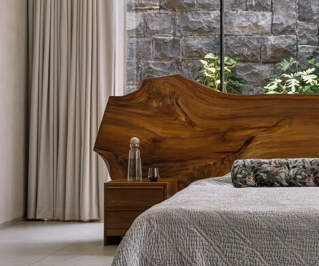 In our GAIA project in Chennai, we designed this master bedroom to be a serene retreat. The live-edge wood headboard brings a raw, natural element indoors, set against a rugged stone wall that connects the space to the earth, reflecting our modern organic and Wabi-Sabi design principles.