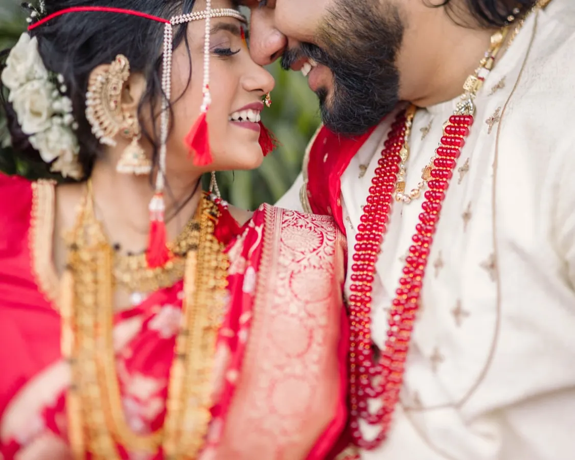 The story is in the small, silent conversations. This candid photograph captures the pure joy and intimacy of a newly married couple, focusing on their smiles and the gentle touch that says everything. It's a perfect moment from a beautiful Maharashtrian wedding.