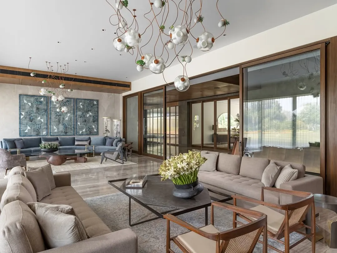 The expansive living room of the K Residence, designed to be both a grand space for entertaining and an intimate family area. The design incorporates large sliding doors to flood the room with natural light and features custom furniture and curated art, including exquisite Bocci lights.