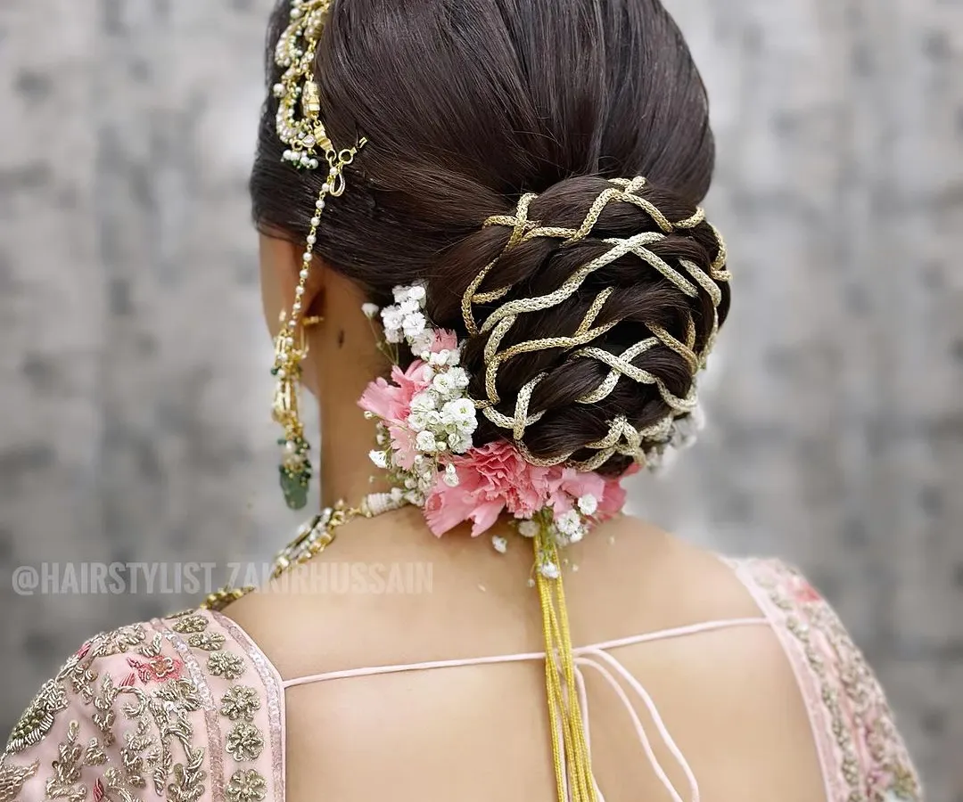 For this bridal bun, I wove intricate patterns using golden thread to create a unique basket-weave effect. The look was finished with fresh pink carnations and baby's breath, adding a touch of softness to the structured updo.