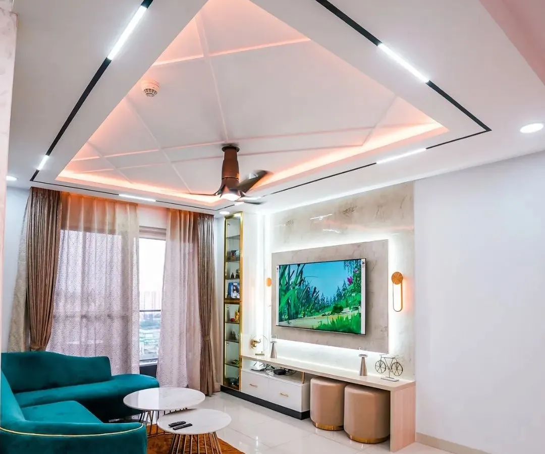 A modern living room designed for comfort and conversation. I focused on creating a sophisticated look with a striking false ceiling featuring geometric patterns and layered lighting, a plush teal sofa for a pop of color, and a sleek, minimalist TV unit. This space perfectly balances style and functionality.