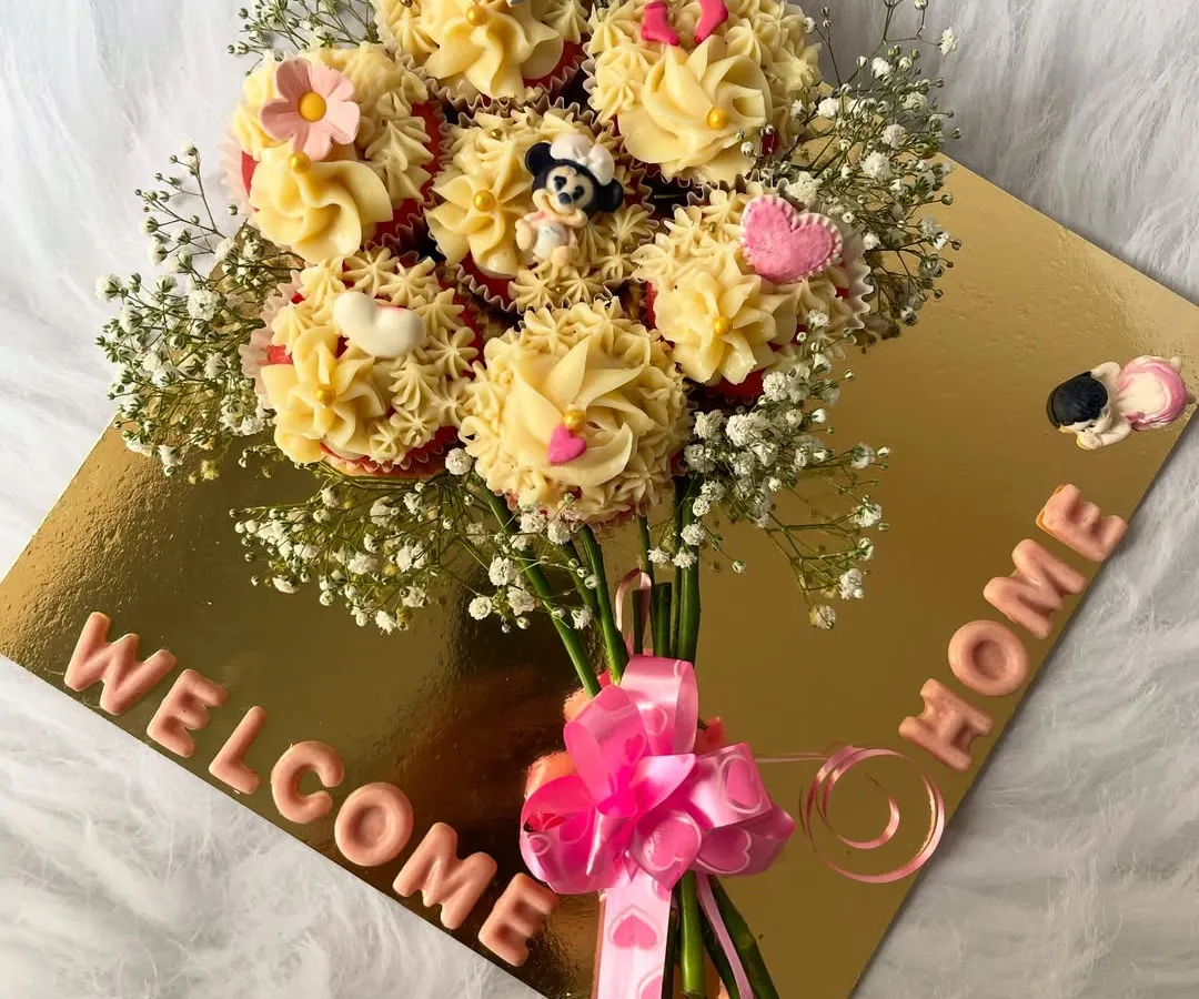 Say it with sweetness with our edible cupcake bouquet. This unique arrangement features beautifully frosted cupcakes presented as a floral bouquet, complete with a "Welcome Home" message, making it a delightful and memorable gift for any celebration.