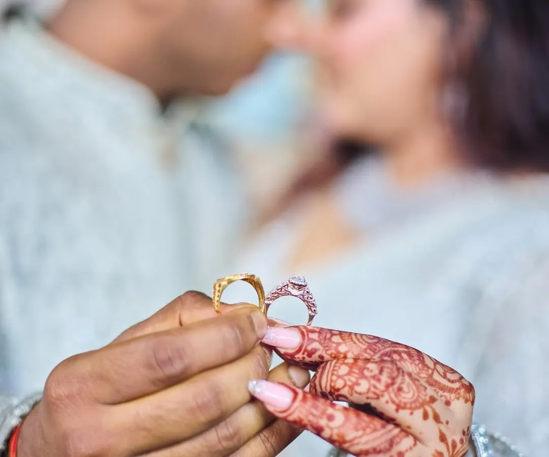 This close-up shot focuses on the engagement rings, a powerful symbol of the couple's promise. I use a shallow depth of field to draw attention to the rings and the bride's henna, with the couple sharing an intimate moment in the background.