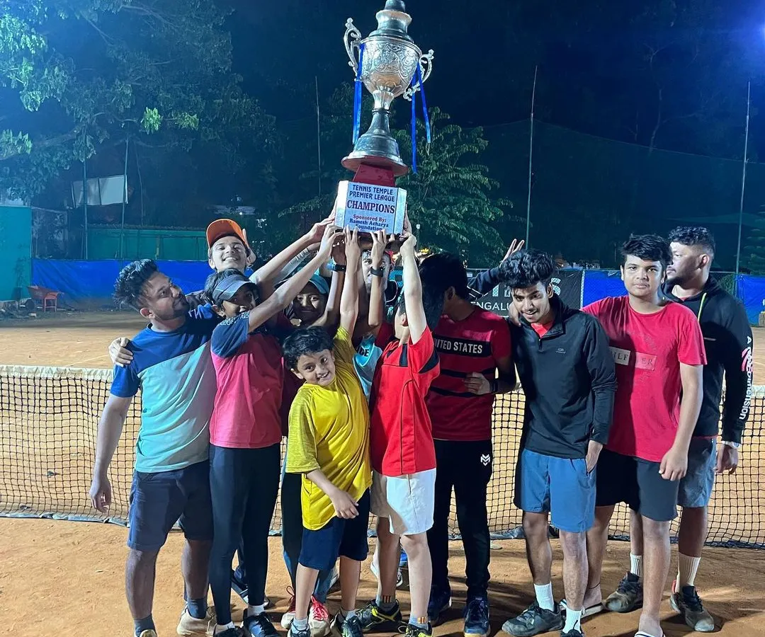 The ultimate moment of victory in our Tennis Temple Premier League. A team celebrates hoisting the championship trophy under the floodlights, capturing the spirit of competition and teamwork that defines our league.