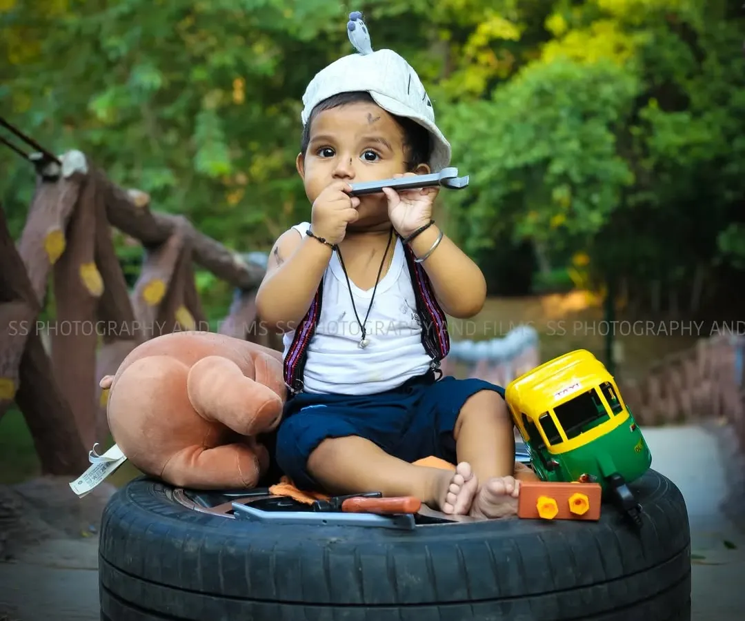 This creative "little mechanic" themed photoshoot for a toddler was set up outdoors. We used a variety of props like a tire, tools, and toys to build a fun and playful scene that captures his curious personality.