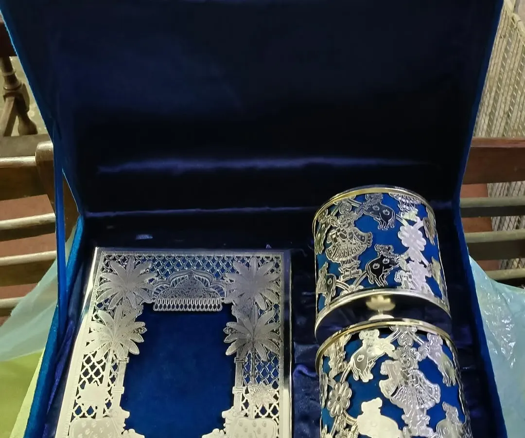 This is an example of a truly luxurious wedding invitation set. It features an intricate silver laser-cut card and matching favors, all presented in a royal blue velvet box, designed to be a treasured keepsake.