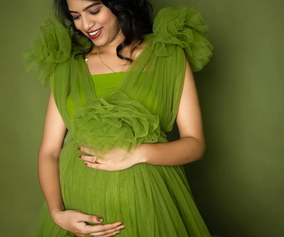 Celebrating life and growth with this beautiful mom-to-be. The vibrant green of this ruffled gown symbolizes new beginnings, perfectly complementing her radiant glow in this studio maternity portrait.