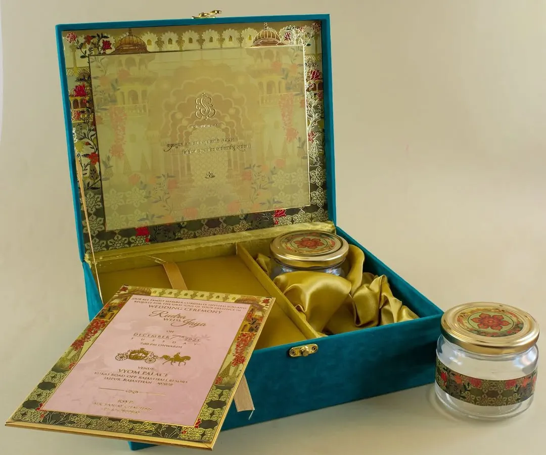 For a truly grand statement, I create custom boxed wedding invitations. This teal velvet box opens to reveal the main invitation card, separate inserts for different events, and custom-fitted compartments for gifts like dry fruits or sweets.