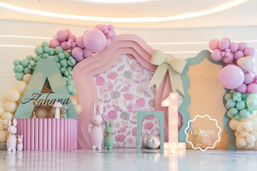 Welcome to "Aahana's Onderland," a whimsical first birthday party where every detail was crafted to inspire wonder. This custom-fabricated backdrop, with its soft pastel balloons and floral-print panels, set the stage for a magical celebration.