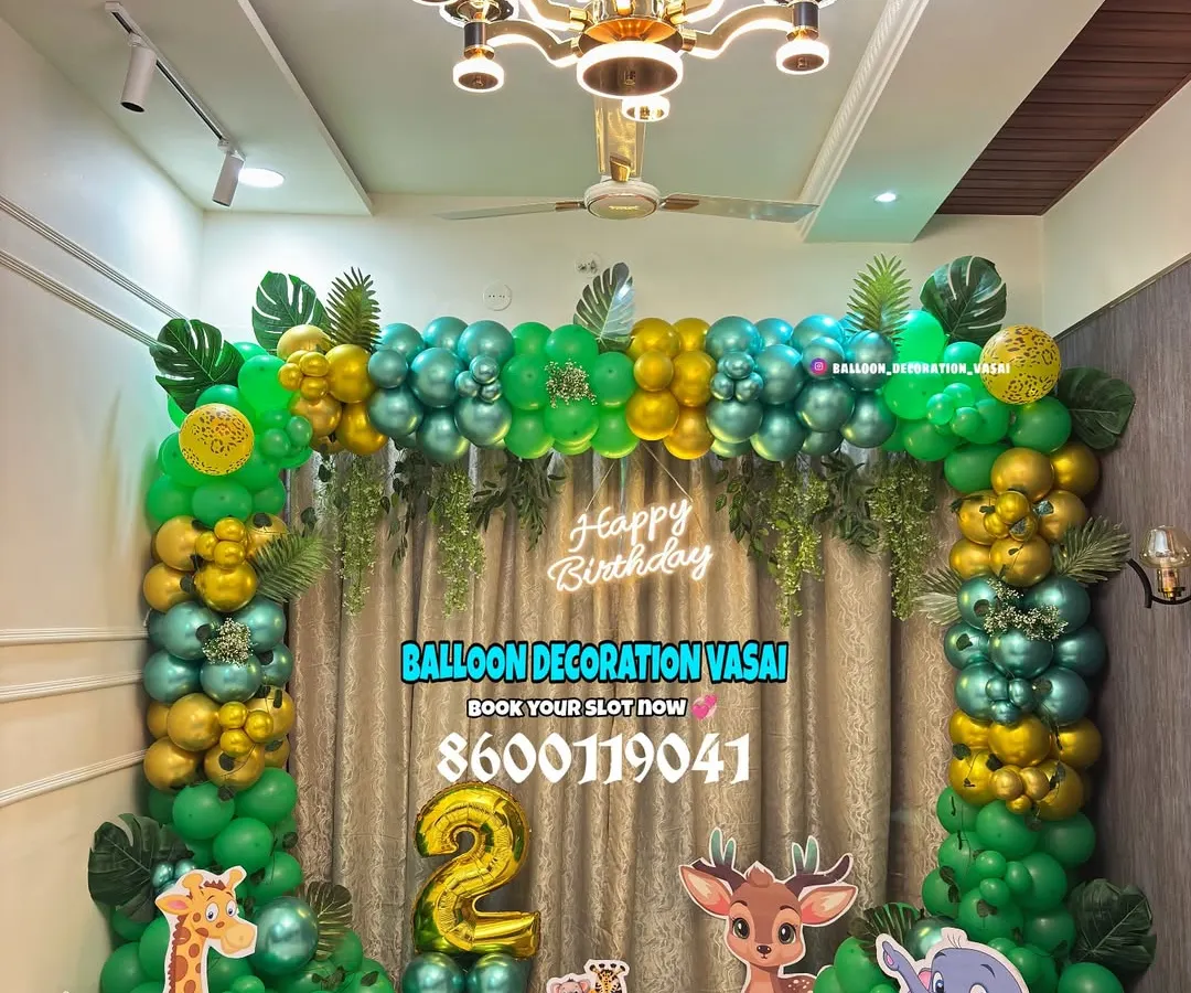 We brought the jungle to life for this 2nd birthday party. This setup includes a full balloon arch with green, gold, and teal chrome balloons, jungle leaf accents, and life-sized cutouts of a giraffe, deer, and elephant.