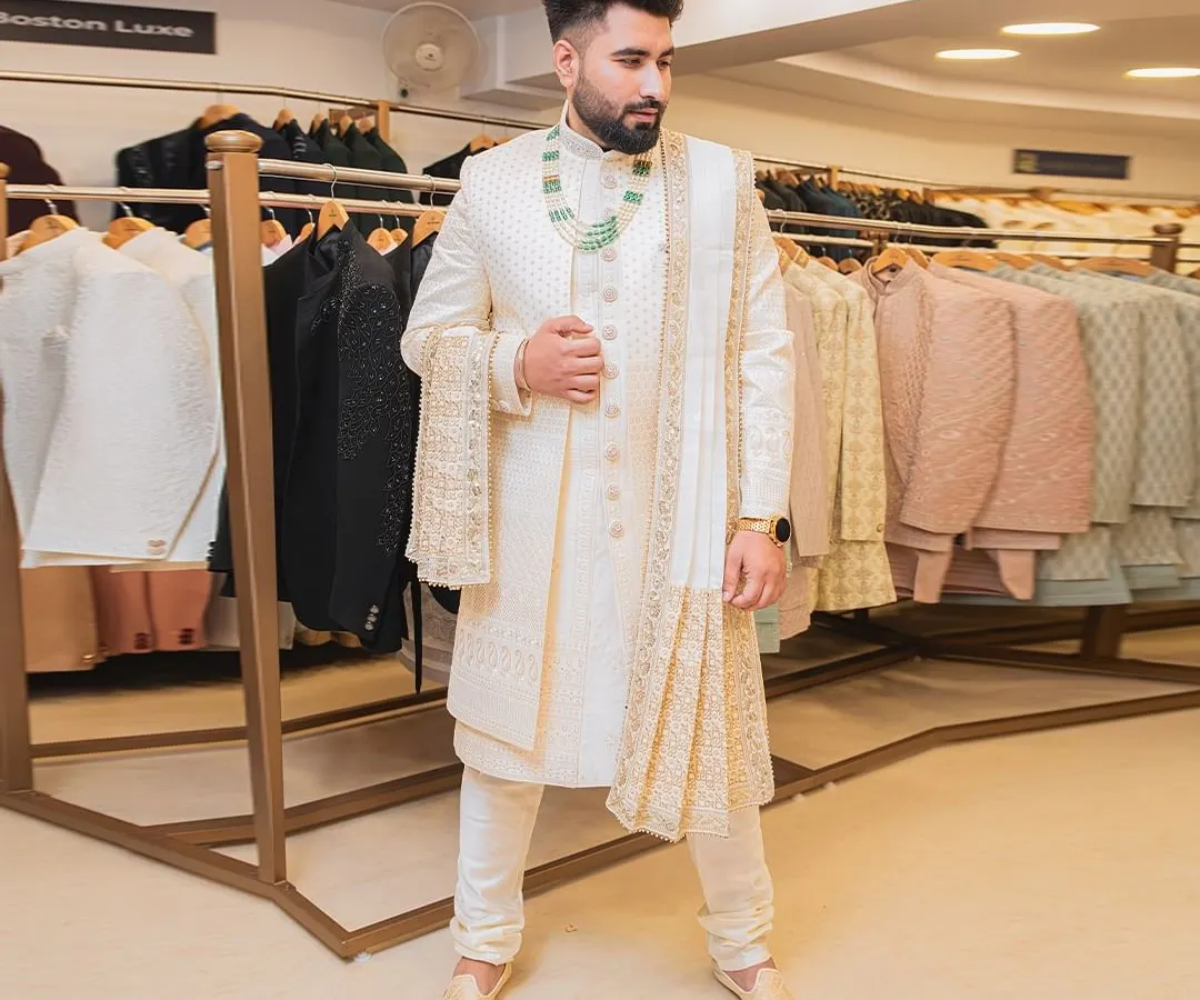 For the groom who wants a timeless and royal look. This classic ivory sherwani features delicate gold embroidery, a matching stole, and elegant accessories. We help you get the complete dulha look for your big day.