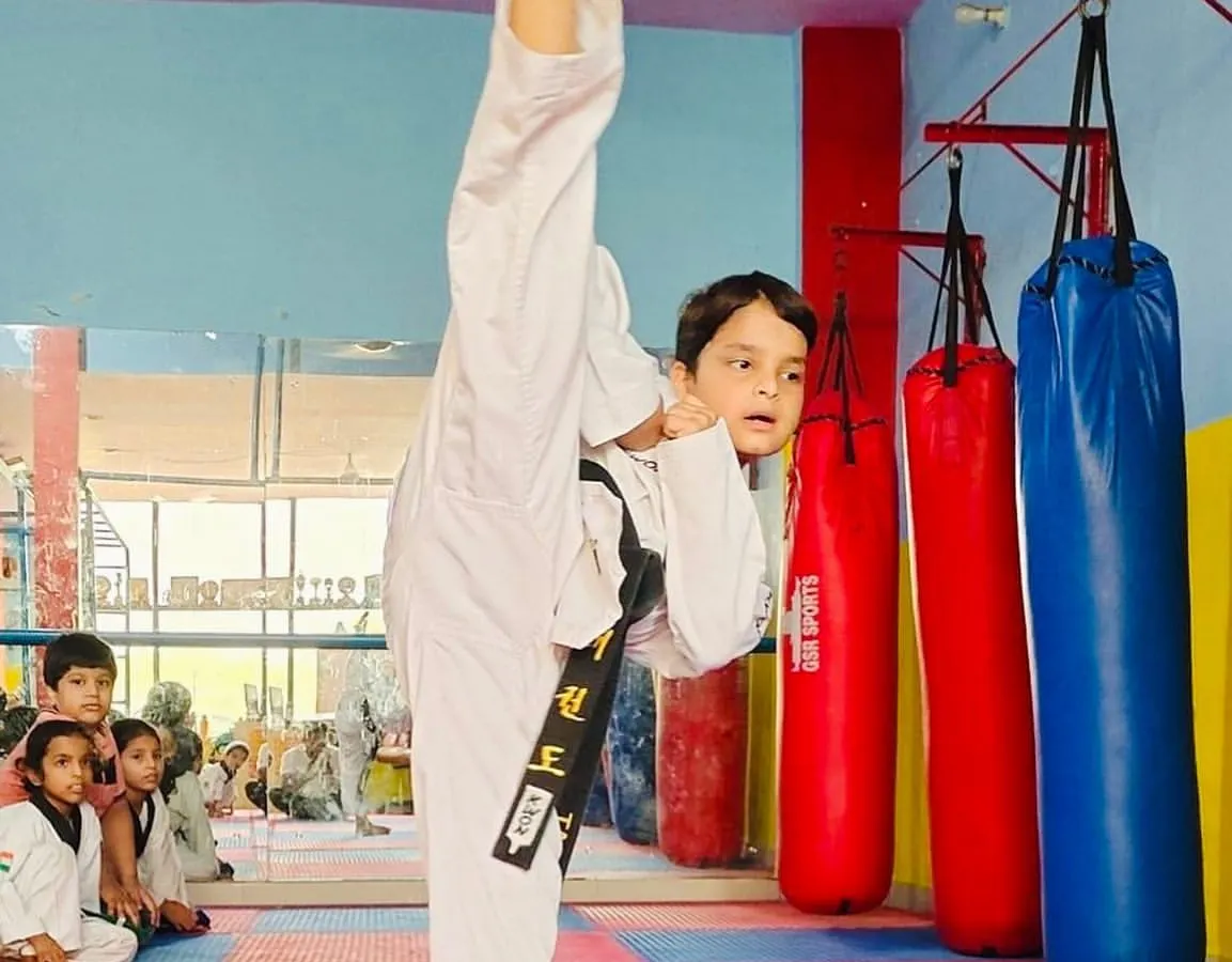 A demonstration of pure flexibility and technique. This student is executing a perfect vertical high kick, a fundamental skill in Taekwondo that requires immense practice and control.