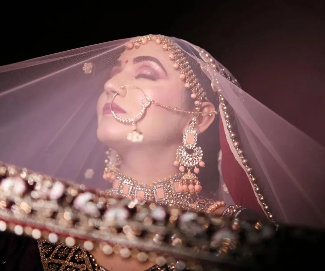 A classic bridal portrait with a modern, artistic touch. We use light and shadow to capture the bride's serene beauty and anticipation from behind her veil.