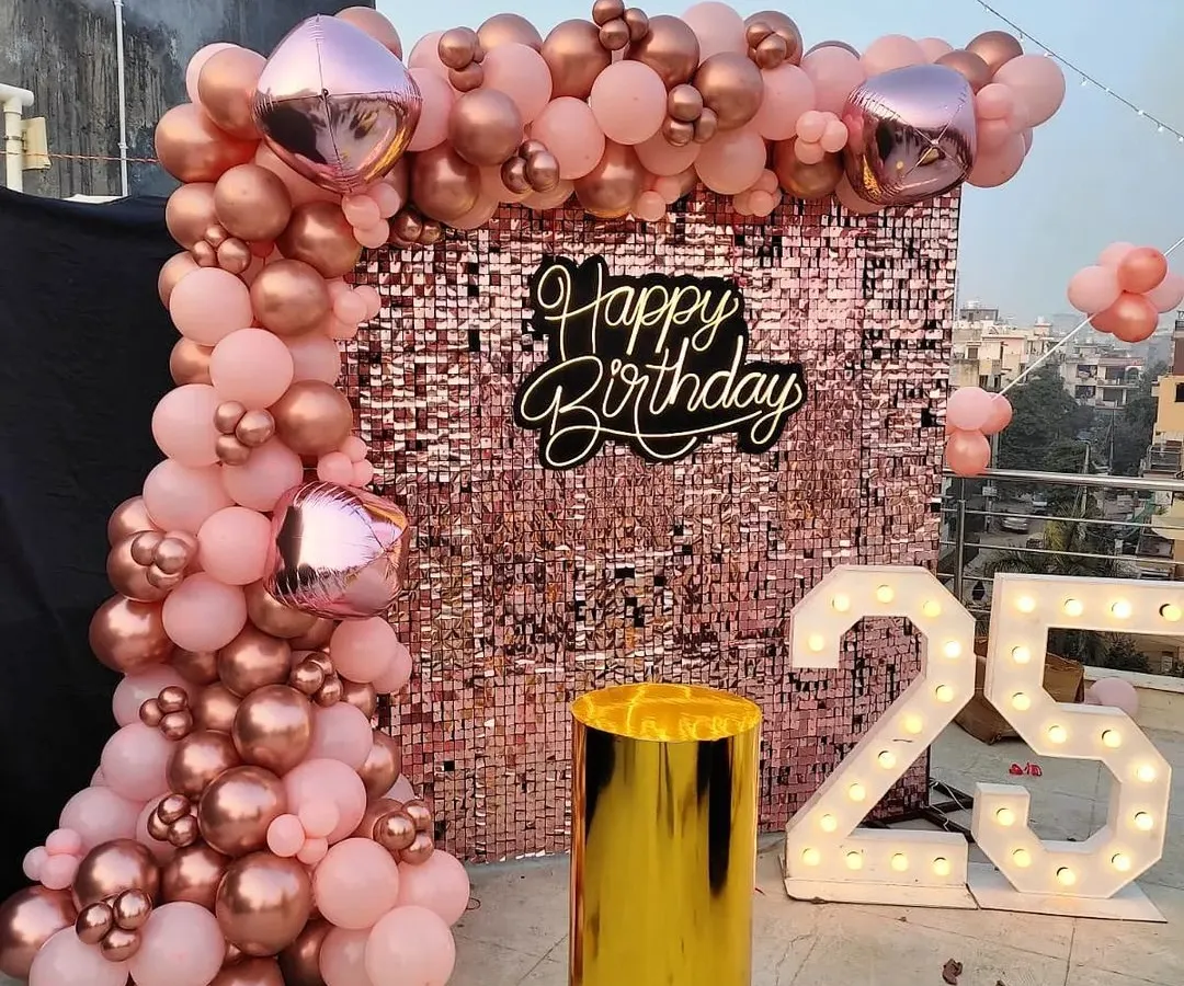 Celebrating a 25th birthday in style with a glamorous rose gold theme. The shimmering sequin wall creates a perfect photo opportunity, complemented by a matching organic balloon garland and bold, illuminated marquee numbers.