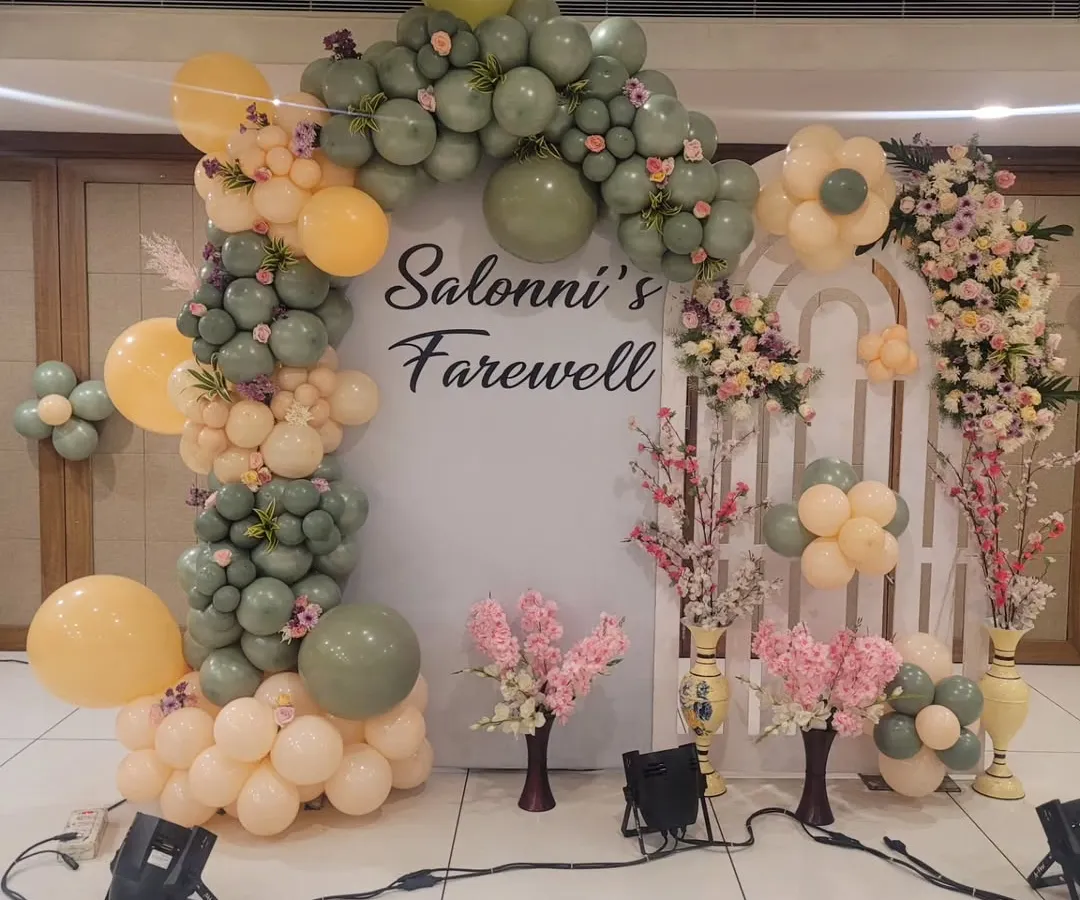 For this farewell party, I created a stylish photo booth using a custom backdrop and an organic balloon arch in trendy sage green and peach tones. This setup combines fresh flowers with modern balloon artistry for a memorable celebration.