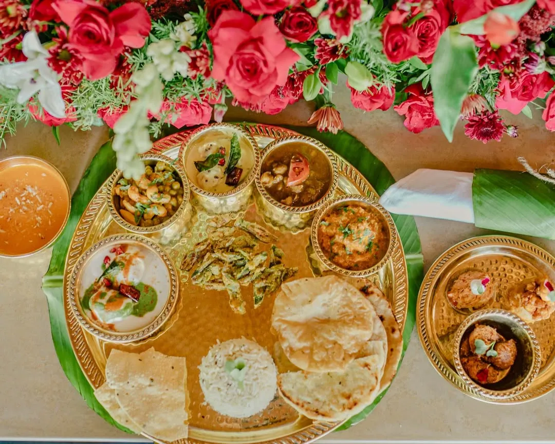 We believe in the beauty of tradition. This overhead view captures our meticulously arranged Jain thaali, a complete sensory journey through authentic Indian flavours, presented with modern elegance.