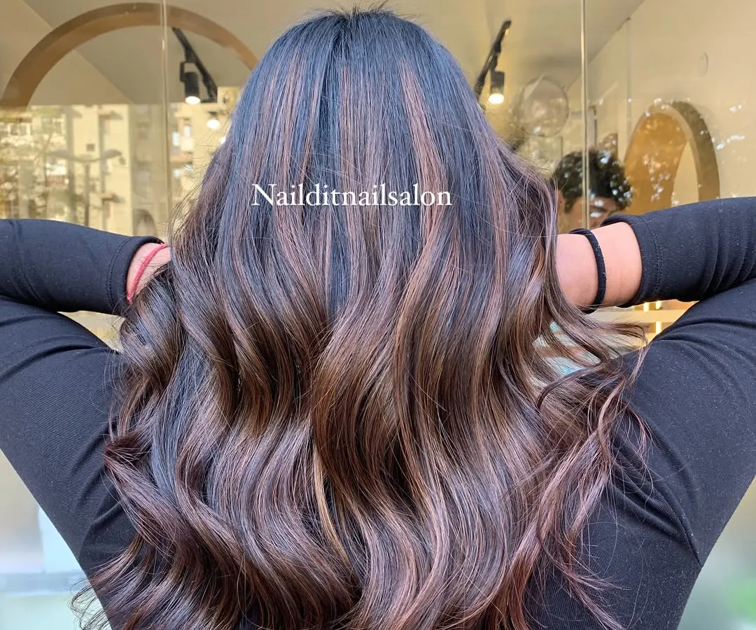 A perfect example of how highlights can add dimension to dark hair. We created these rich, caramel and light brown streaks, blending them seamlessly into the natural base color and styling them into soft waves to showcase the texture.