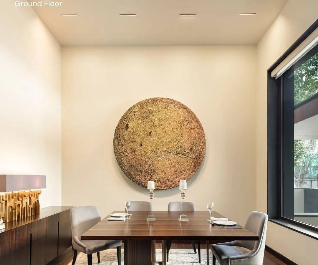 The dining area in our Vasant Vihar residence is anchored by a striking piece of art, creating a focal point for shared meals and conversations. We design spaces that are not just functional but also serve as a backdrop for life's moments, using a palette of warm, natural materials and refined finishes to build an atmosphere of quiet luxury.