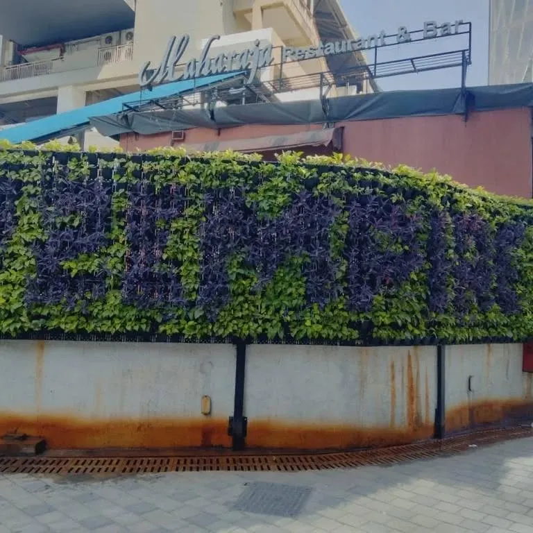 We help businesses stand out with custom-branded green walls. For this restaurant, we designed a living sign using contrasting purple and green plants, creating an unforgettable, eco-friendly facade that welcomes guests.