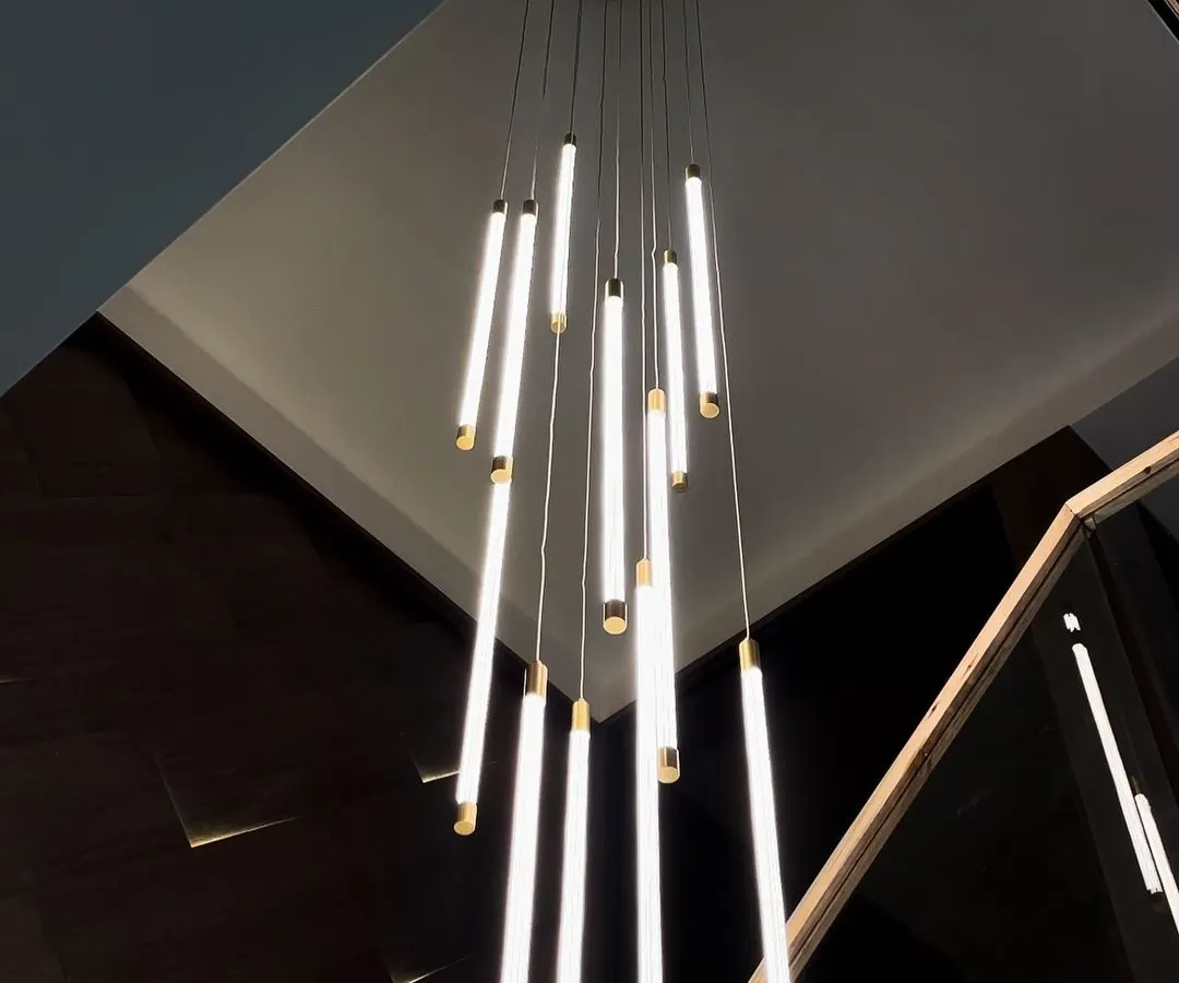Our height-adjustable Wand Chandelier brings customizable brilliance to any space. This installation in a modern home demonstrates how the fixture can be adapted to create a dramatic, cascading effect over a staircase, making it a true centerpiece.