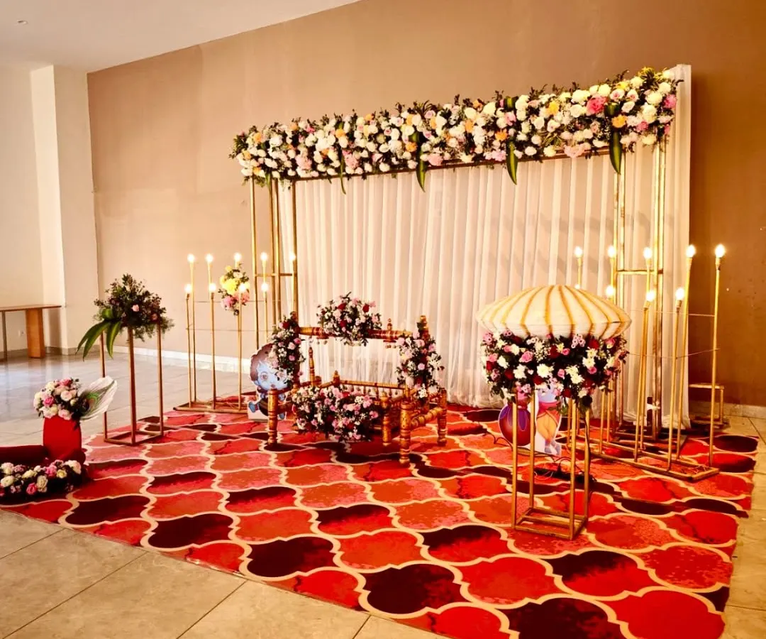 We designed this grand and traditional naming ceremony with a beautiful floral theme. The setup includes a flower-adorned cradle, a backdrop of white drapes and a dense floral runner, and warm lighting to create a classic, welcoming atmosphere.