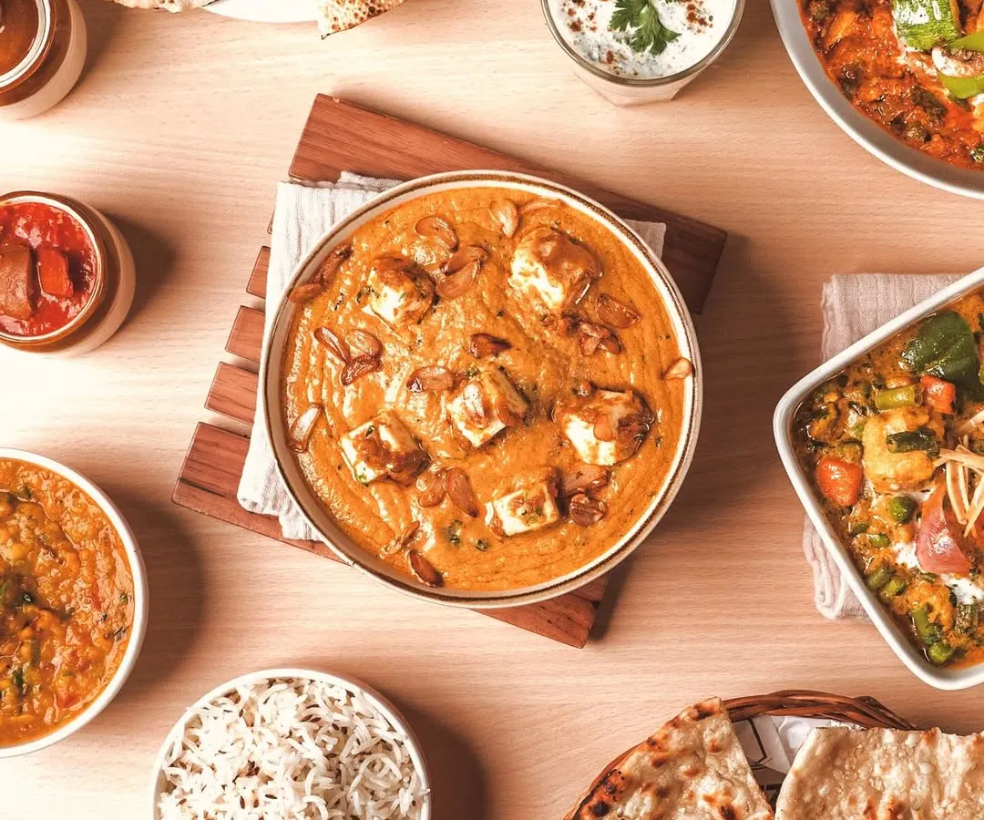 A vibrant top-down view of a classic Indian meal. My food styling focuses on arranging dishes like this paneer curry, naan, and rice to create a full, inviting picture that’s perfect for menus and social media.