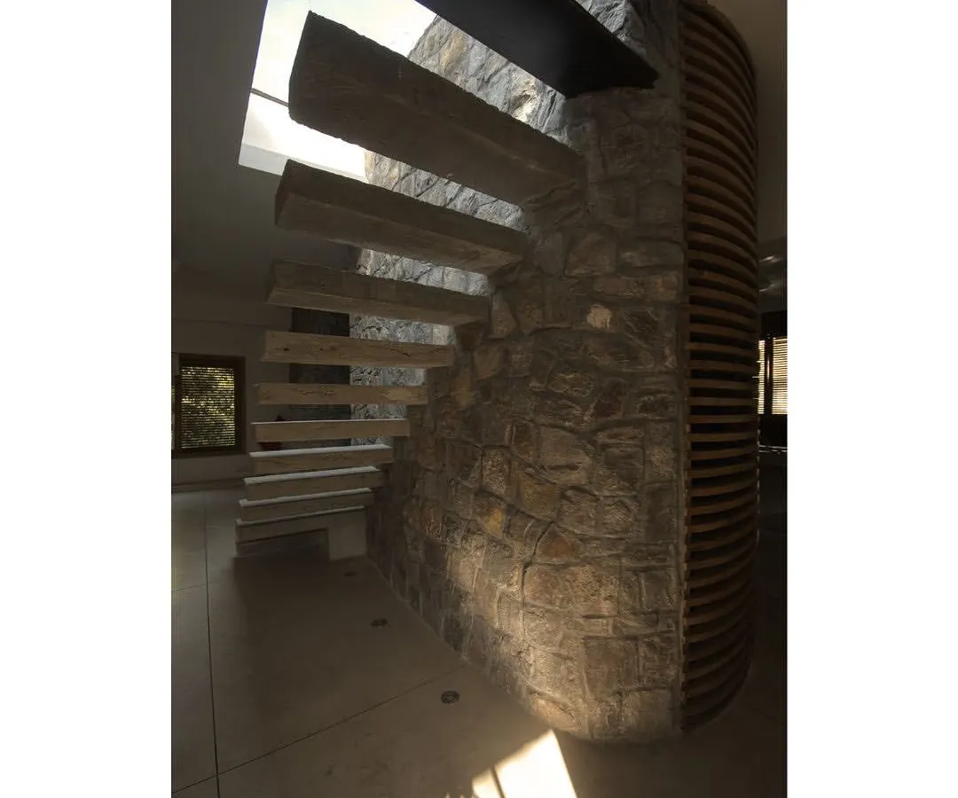I believe staircases should be sculptural centerpieces. In this apartment for filmmakers, cantilevered concrete steps emerge from a random rubble stone wall, creating a dramatic ascent towards a skylight that bathes the space in natural light.