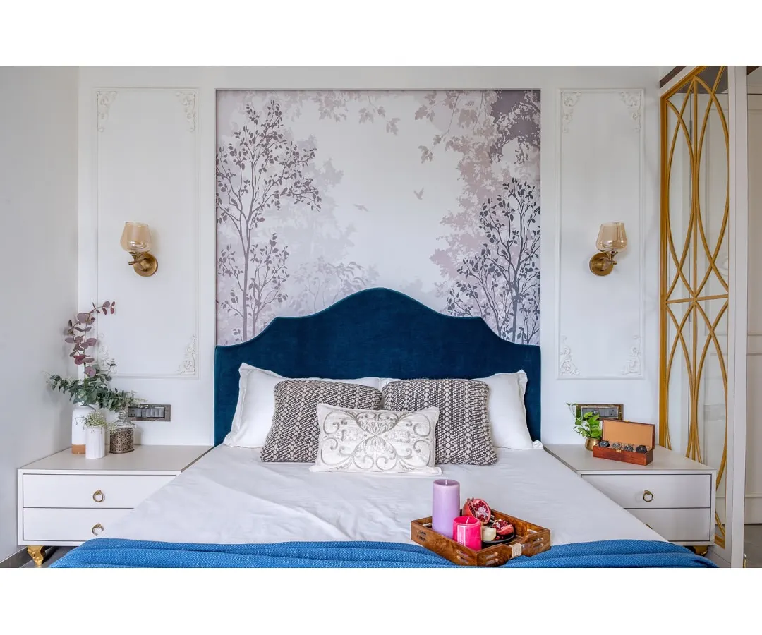 A master bedroom designed as a serene retreat. We balanced a rich blue velvet headboard and a delicate nature-inspired wallpaper with classic wall mouldings and warm lighting to create a space that feels both luxurious and deeply personal.