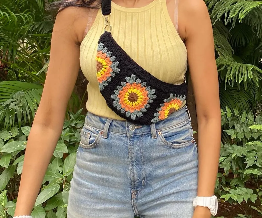 Our crochet granny square fanny pack is perfect for when you want to be hands-free. This design features a bright sunflower motif on a black base, combining trendy style with handmade charm. It includes a zip and an adjustable strap for comfort.