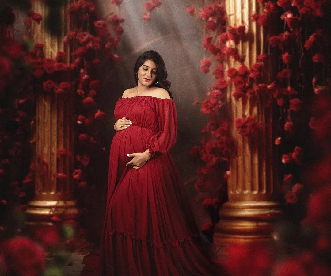 In my studio, we can create bold and moody portraits. Here, a beautiful mom to be is surrounded by red roses and dramatic lighting, creating a powerful and romantic image of motherhood.