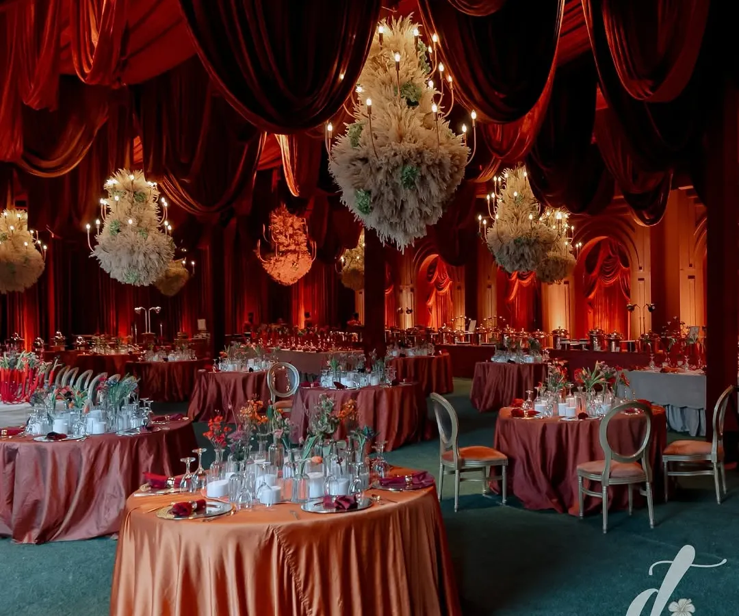We transformed this space into a dramatic and opulent reception hall using a rich, red color palette and luxurious velvet draping. The scene is set with dozens of floral chandeliers, creating a warm, intimate, and truly grand atmosphere for an evening celebration.