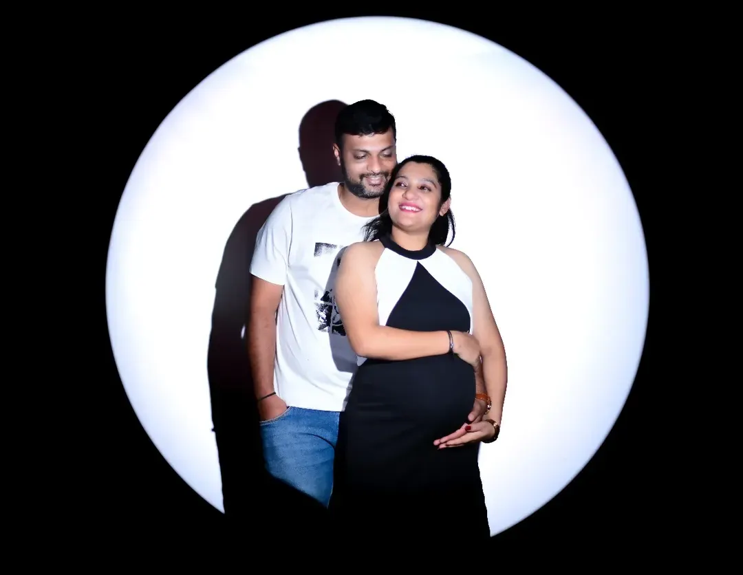I love including partners in the photoshoot to capture the shared joy of this special time. This dramatic spotlight portrait is a great example of how I create artistic and intimate images for couples, focusing on your connection and anticipation.