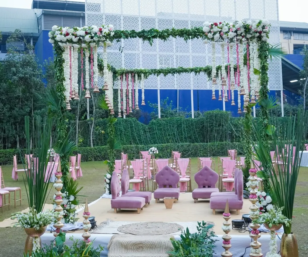 For a fresh and romantic daytime wedding, I designed this garden mandap using a vibrant pink and green palette. The structure is covered in greenery, with hanging floral strings of rajnigandha and roses, and traditional bells for a touch of South Indian charm.