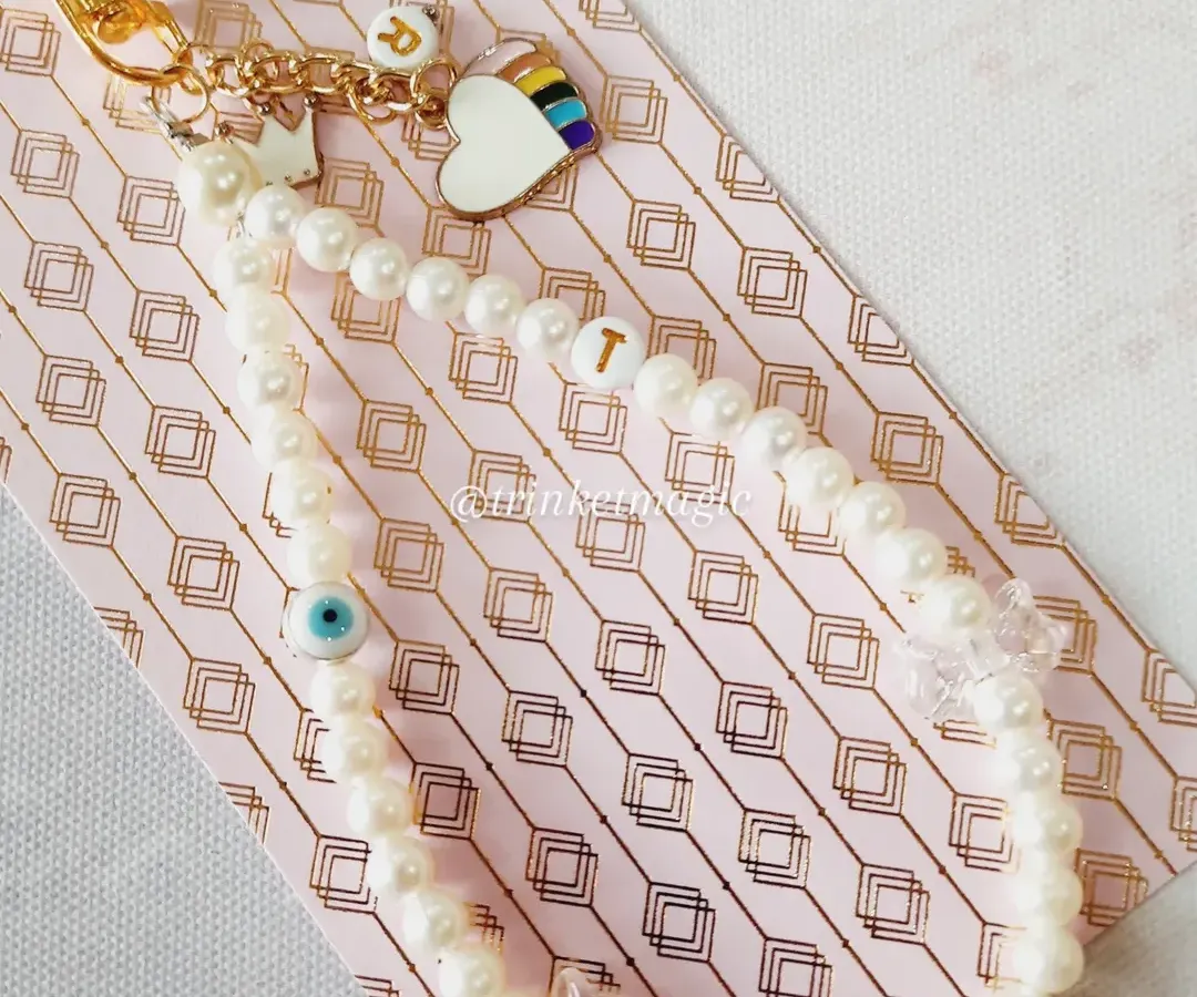 I love making your stories into something you can carry every day. This custom phone charm was made with love, featuring the owner's initial 'T', her daughter's initial 'R', a rainbow heart, and a protective evil eye, all tied together with elegant pearls.