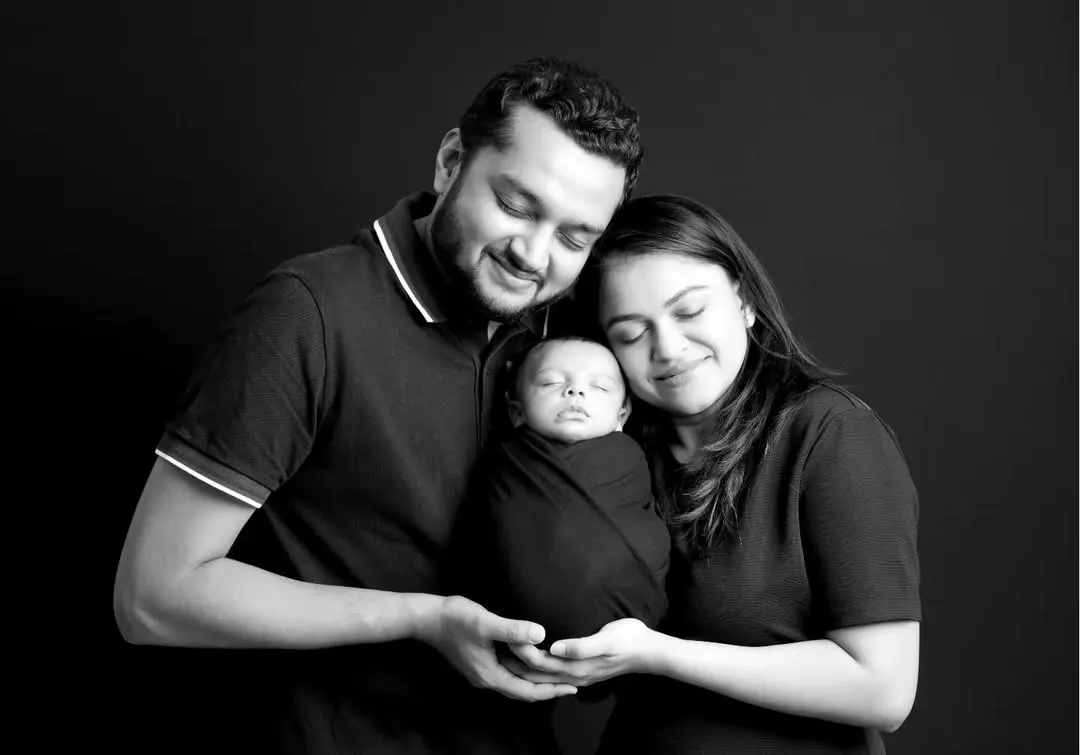 We believe these first family portraits are priceless. This classic black and white shot captures the pure love and connection between new parents and their sleeping baby, a memory to cherish forever.