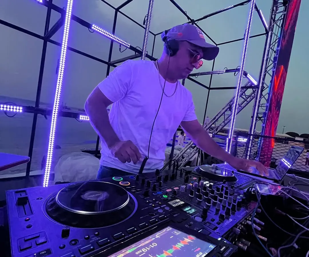Setting the vibe for a sundowner wedding event. This shot captures me in my element, mixing tracks on my Pioneer DJ setup against a beautiful sunset, with a custom lighting rig ready for the night ahead.