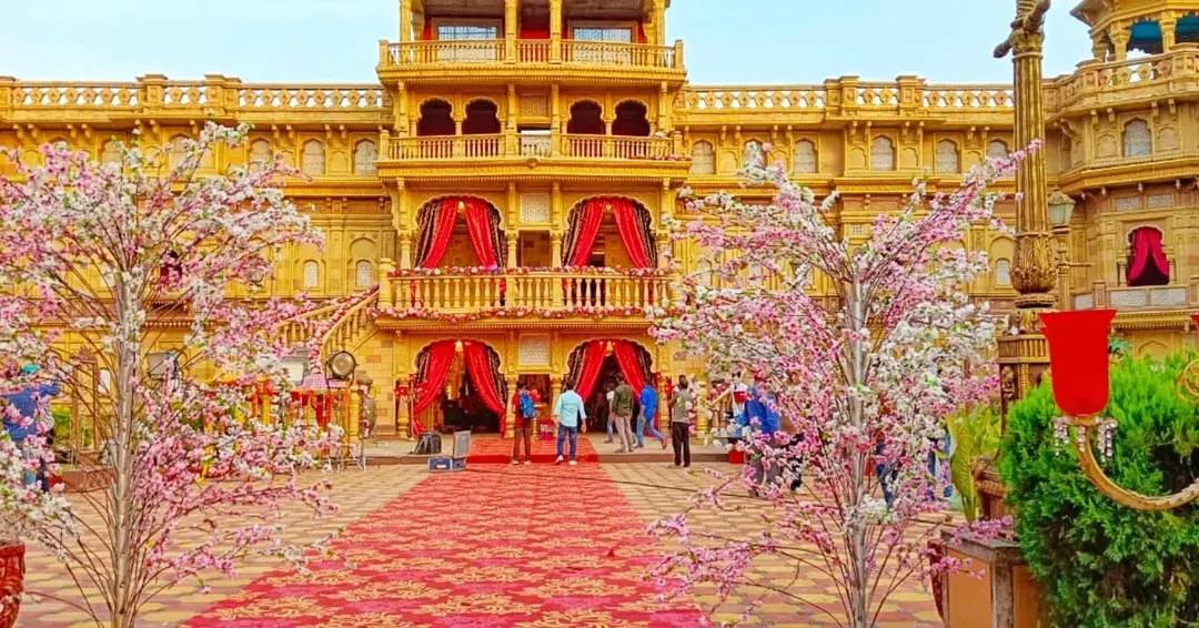 A palace-front wedding venue transformed with cherry blossom trees and a grand patterned red carpet, showing how I handle large-scale, opulent wedding decorations.