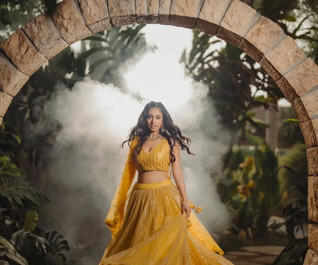 This image blends vibrant ethnic fashion with a touch of magic. The movement of the lehenga, the stone archway, and the atmospheric smoke create a captivating scene for a designer lookbook or campaign.