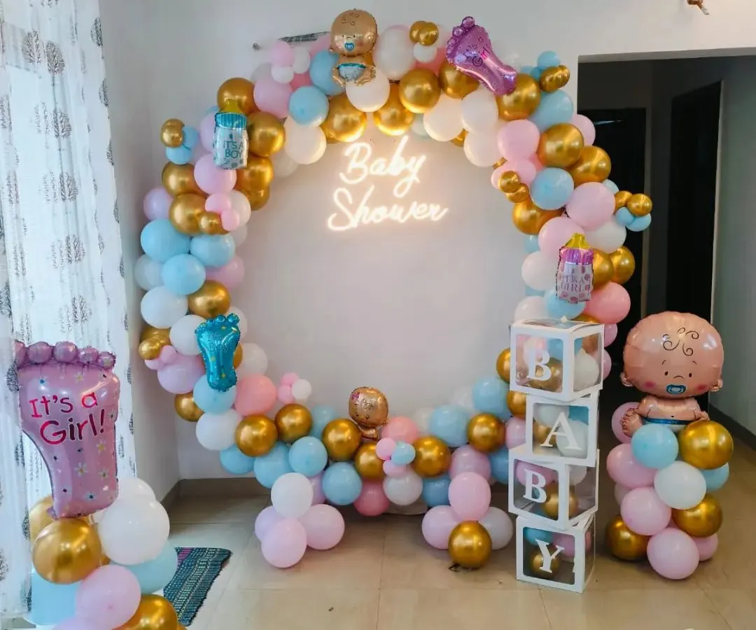 This vibrant baby shower decoration features a full circular balloon arch in pink, blue, white, and gold. The design is centered around a "Baby Shower" neon sign and includes transparent "BABY" blocks and character foil balloons, creating a complete and festive photo corner.